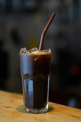 Black coffee in a glass, placed on a wooden table in a cafe