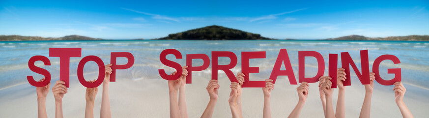 People Hands Holding Colorful English Word Stop Spreading. Ocean And Beach As Background