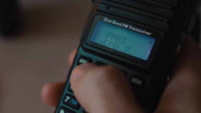 Hand Hold On The Walkie-talkie And Change Radio Channels Indoors Close-up Macro