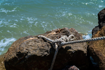 Fototapeta na wymiar Copy space and shade. A rope tied with large stone for anchorage at the coast.