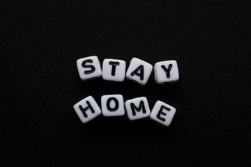 Obraz premium Stay Home, Word written by Cube letters, Stop Corona Virus, Message for people white cubes on a black background, no person, space for text and horizontal