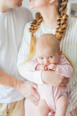 Beautiful young parents are holding their little newborn daughter in their arms. Blue-eyed little girl of 2 months. Baby