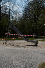 Playground with a  slide closed with streamer or barrier tape due to restrictions social distancing and curfew during the Corona Covid-19 pandemic