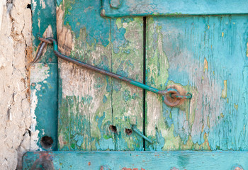 The closed door is locked, the old hook on the wooden door with which the paint peeled off
