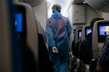 A flight attendant on a plane in protective clothing and medical gloves during the Corona crisis; ...