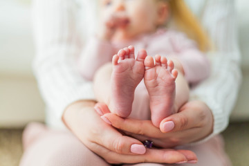 Close-up. Beautiful young mother holds in her hands the legs of her little daughter. Baby. Newborn.