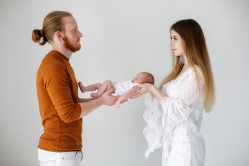 Parenthood, love and family concept - Smiling mother and father holding their baby son.Happy European family, father mother and son baby. Young parents with a newborn son in their arms in the Studio o