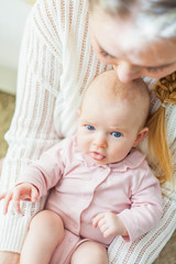 A beautiful young mother holds in her arms a small pretty blue-eyed 2-month-old daughter. Newborn.