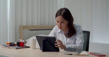 Asian young woman working from home with tablet