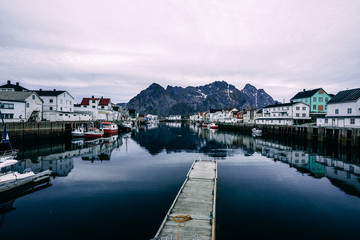 Fototapeta na wymiar henningsvaer harbour with boats on the side and mountain in background