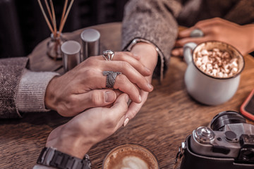 Happy couple holding hands on table in cafe