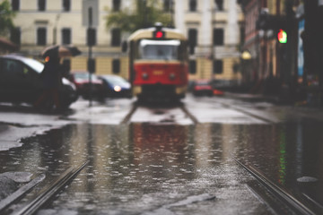 Scene of rainy european city in retro style. Selective focus on puddle and tram on background. Location - Square of Contracts (Kiev)