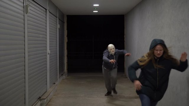 Woman running away scared from zombie through a dark night tunnel with a flickering light. Zombie apocalypse concept