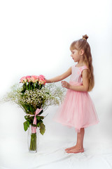 A little girl in a pink dress with long hair, with roses, smiling, on a white background, huge bouquet of roses, vertically