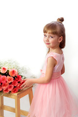 A little girl in a pink dress with roses, smiling, on a white background, vertically