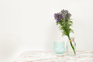 Blue coffee mug with the vase of lavender flowers on a marble table