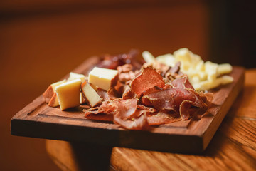 A large board with a wide selection of snacks for beer. Meat carpaccio and cheese. Tasty snacks,...