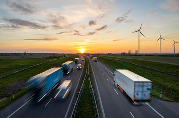 truck traffic on the highway at sunset - obrazy, fototapety, plakaty