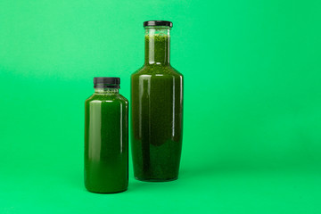 Fresh celery spinach juice in a plastic and glass bottle, isolated on a green background. Healthy diet detox juice.