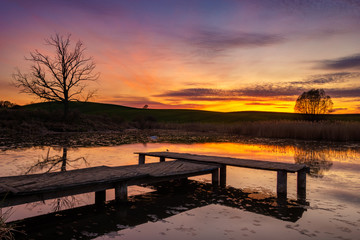 Fototapeta na wymiar wooden jetty at a small lake during a beautiful sunset