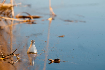 Naklejka premium Old plastic bottle floating in water. Environmental pollution. The fight against economic crimes