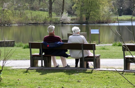 Älteres Ehepaar auf einer Parkbank am See im Frühling