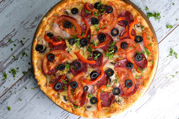 Flat lay photograph of tasty Italian pizza on grey rustic wooden background. Copy space banner.