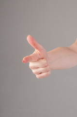 Woman hand showing forefinger in gun sign on a white isolated background