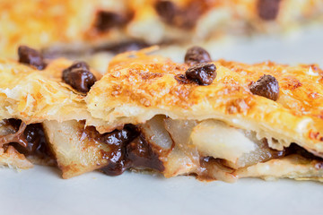 Close up of a slice of baked puff pastry stuffed with pear and chocolate chips. 