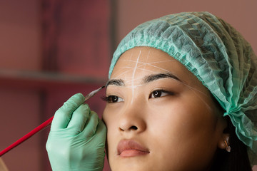 Eyebrow tinting and dyeing. The master paints eyebrows with henna to a beautiful girl, paints with...
