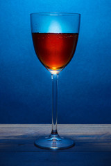 Glass of fortified red wine, blue color light, warm brown glow.