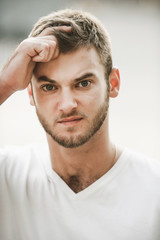 Fototapeta premium smiling friendly guy with a variety of emotions; a man in a white T-shirt and jeans with a clock on his hand;