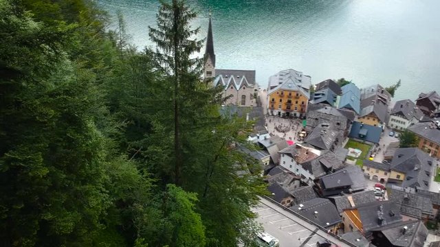 Scenic Aerial footage of small village/town named Hallstatt in Austria with the iconic church as subject .