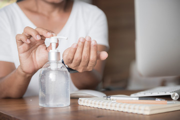 Female washing hand  by sanitizer gel for prevention coronavirus disease (COVID-19) before work from home.