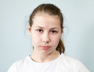 Young Caucasian girl with a sad expression on her face. Portrait on grey background, emotions series