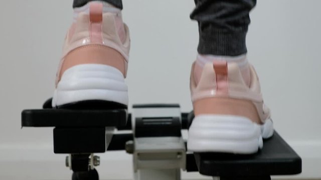 Close up woman foot working out on the stepper exercise machine at the gym, stepper machine on the wooden floor.