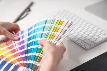 Graphic designer chooses colors from palette guide for painting and printing a new creative...