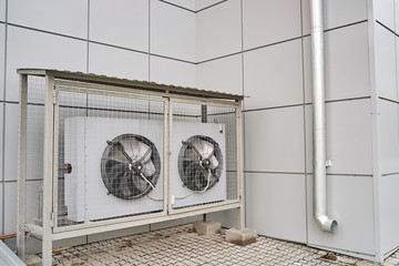Outdoor air conditioning on the wall of a house in a protective cover