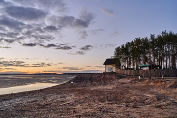 Unusual autumn landscape at sunset in a village on the lake.