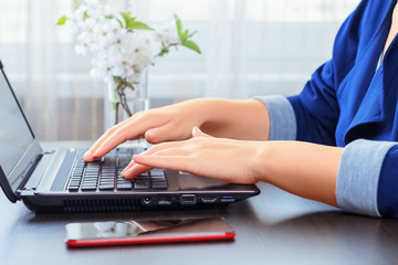 Closeup side view on hands of a young woman typing on laptop from home office. Work from home, distance learning, quarantine concept