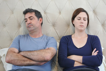 Bored couple in home bedroom looking away