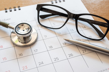 stethoscope and calendar on wooden table, schedule to check up healthy concept