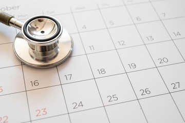 stethoscope and calendar on wooden table, schedule to check up healthy concept