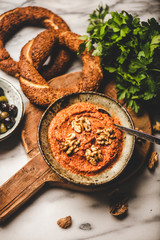 Flat-lay of Turkish traditional spicy smoked red pepper paste with walnuts, simit bagels, parsley and olives over breakfast table, top view. Typical Turkish breakfast dish
