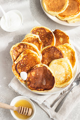 Homemade pancakes with honey and sour cream, sunny shadowed table surface. Light grey concrete background. Natural light and shadows food photography concept. Breakfast. Top view. 