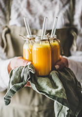 Immune boosting vitamin health defending drink. Woman bottles with fresh turmeric, ginger and...