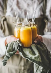 Poster Immune boosting vitamin health defending drink. Woman bottles with fresh turmeric, ginger and citrus juice shots in hands, selective focus. Pure vegan Immunity system booster © sonyakamoz
