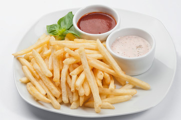 French fries with two sauces on a white plate on a white background.
