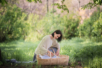 Fototapeta premium Mom carries her son in a wicker basket. Family picnic in nature. New life after quarantine and self-isolation.