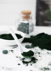Spirulina powder and pills on white table